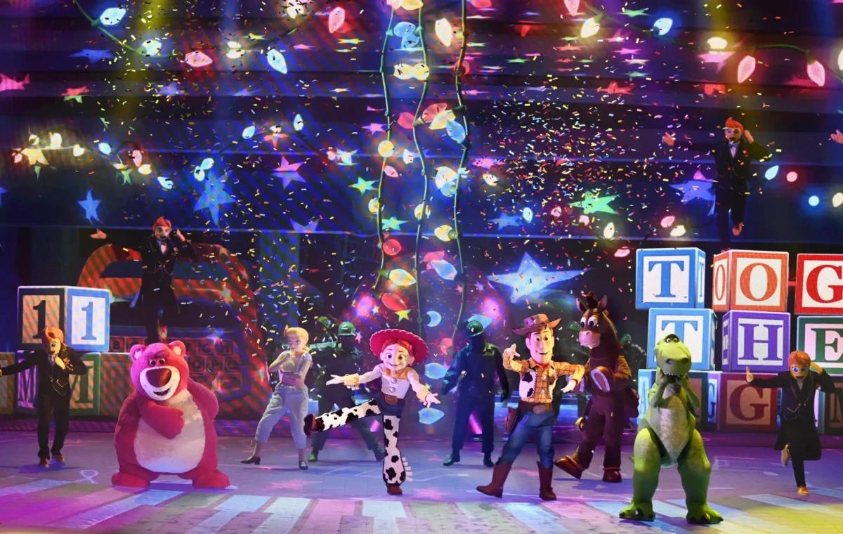 Spectacle coloré à Disneyland Paris avec les personnages de Toy Story, incluant Woody, Jessie, Lotso et Rex, sur une scène remplie de lumières et de confettis, célébrant un moment festif et magique.